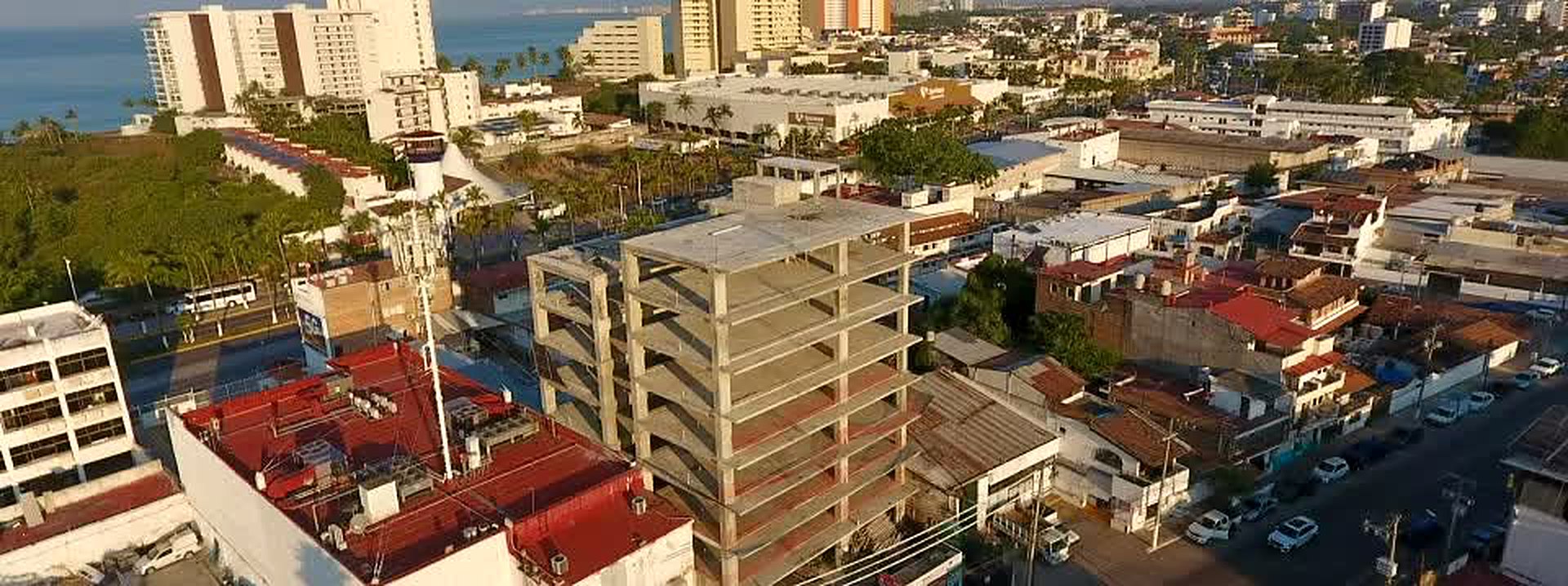 Vista aérea real de la obra de Quartier: la estructura de concreto de ocho niveles terminada, entre las casas de la Colonia Olímpica, con la Zona Hotelera y el mar al fondo